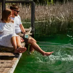 Para spędza miło weekend nad jeziorem, siedząc na pomoście i mocząc nogi w krystalicznie czystej wodzie.
