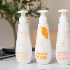Trzy białe butelki z pompką: emulsja myjąca, balsam dermo i balsam regenerująco-kojący. Idealne kremy na AZS dla dzieci.
