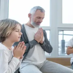 Dziadek z wnukami w ciszy składają dłonie do modlitwy o zdrowie dla rodziny.