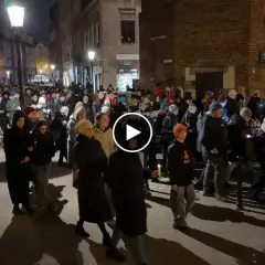 Tłum ludzi idzie ulicą nocą, trzymając świece. To wygląda jak Droga Krzyżowa.