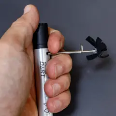 A hand holds a silver "DART" marker with a small, black, propeller-like attachment. This is part of a stans dart review.