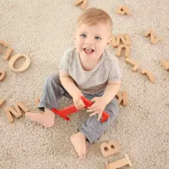Bambino sorridente circondato da lettere di legno, un modo divertente per iniziare a capire come sviluppare il linguaggio nei bambini.