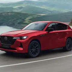 Czerwona Mazda CX-60 3.3 diesel pokonuje zakręt na malowniczej drodze.