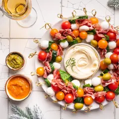 Wieniec z koreczków z pomidorkami, mozzarellą, salami i oliwkami, z dipami i winem.