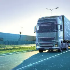 Ein futuristischer LKW fährt auf einer Straße, die von digitalen Daten durchzogen ist. Dies symbolisiert die Zukunft der Logistik und autonome Transportsysteme.
