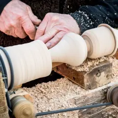 Artisan façonnant du bois sur un tour. Un exemple de ce que faire avec un tour à bois : créer des pièces uniques et élégantes.