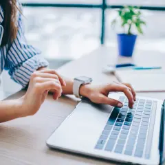 Kobieta pisze na laptopie, szukając informacji, jak anulować przelew mBank.