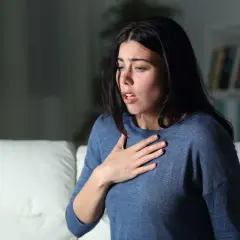 Donna con mano sul petto, respiro affannoso, espressione di chi soffre di attacchi di ansia.