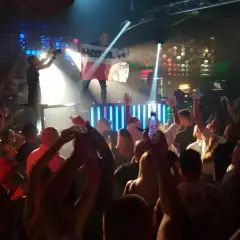 Tłum na parkiecie klubu, DJ na scenie z flagą Polski, światła i energia prawdziwego rave.