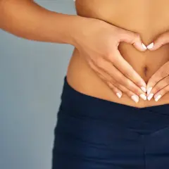 Mani a forma di cuore sull'addome, simbolo di benessere e buona digestione.