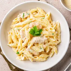 Penne w kremowym sosie, przypominające fettuccine alfredo, z kawałkami kurczaka i natką pietruszki.