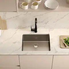 Plan de travail cuisine avec un évier en inox, un robinet noir, une planche à découper en bois avec des poivrons verts et des épinards, et une autre planche en bois.