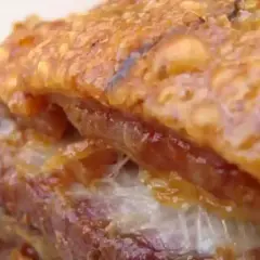 Gros plan sur un délicieux lard rôti au four, la couenne croustillante et dorée, la chair tendre et juteuse. Un vrai régal !