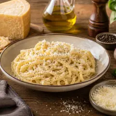 Pyszne spaghetti posypane startym serem, obok kawałek twardego sera włoskiego, oliwa i świeża bazylia.