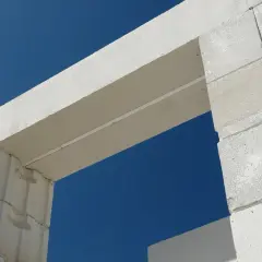 Białe nadproże nad drzwiami 80, wykonane z bloczków z betonu komórkowego, na tle błękitnego nieba.