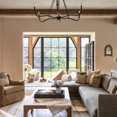 A cozy living room with exposed wooden beams, a large sectional sofa, and a plaid armchair, embodying rustic chic interior design.