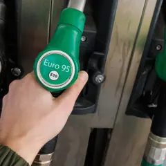 Dłoń trzyma zielony pistolet do tankowania z napisem "Euro 95 E10". Obok widać pistolet do diesla. Czas na tankowanie benzyny!