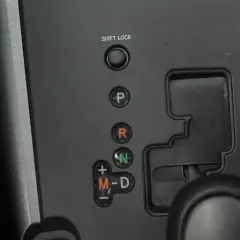 Panel z przyciskami skrzyni biegów: P, R, N, M-D. Obok przycisku "SHIFT LOCK" znajduje się otwór do jego zwolnienia.