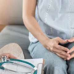 Lekarz notuje podczas rozmowy z pacjentką o zdrowiu jej jajników. Stetoskop leży na dokumentacji medycznej.