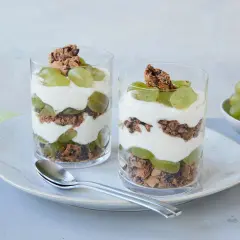 Zwei Gläser mit einem leckeren Trauben-Cookie-Dessert, geschichtet mit Joghurt und Keksbröseln.