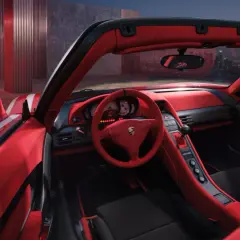 Wnętrze czerwonego Porsche Carrera GT z widokiem na nocne miasto.
