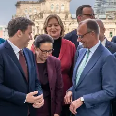 Politiker posieren vor dem Reichstag. Sie scheinen über die Bildung einer Koalition zu sprechen, was bedeutet, dass verschiedene Parteien zusammenarbeiten, um eine Regierung zu bilden.