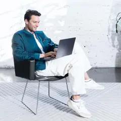 Mężczyzna w wygodnym fotelu planuje, co zrobić z oszczędnościami, korzystając z laptopa.