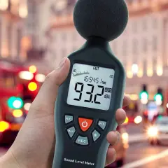 Medidor de sonido en mano, mostrando 93.2 dBA en una calle ruidosa, midiendo la potencia acústica del tráfico urbano.