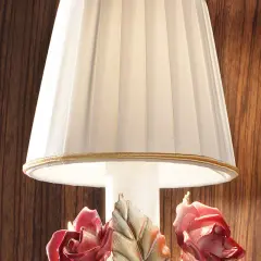 Elegancka lampka nocna z plisowanym abażurem i ceramicznymi różami u podstawy.