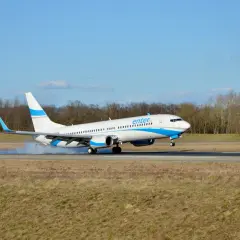 Samolot Enter Air ląduje na pasie startowym, unosząc kurz.