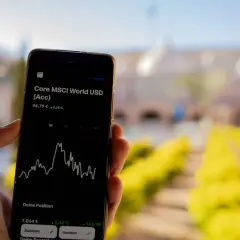 Hand hält Smartphone mit MSCI World Rendite-Chart. Der Kurs steht bei 94,79 € mit einem Plus von 0,25%.
