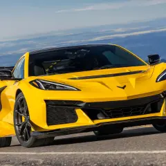 Żółty Chevrolet Corvette C7 ZR1 z dużym tylnym skrzydłem pędzi po górskiej drodze, gotowy na każde wyzwanie.