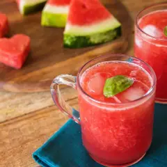 Refrescante bebida de sandía con un toque de limón, servida con hielo y hojas de albahaca.