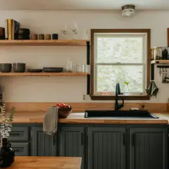 Cozy kitchen with dark gray cabinets, wooden countertops, and open shelving, perfect for an affordable kitchen makeover.
