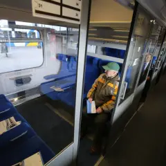 Starszy pan w zielonej czapce siedzi w pociągu. Czy w IC można kupić bilet u konduktora? Pasażerowie w wagonie.