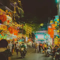 Tętniąca życiem nocą ulica w Ho Chi Minh (miasto), ozdobiona flagami Wietnamu i lampionami.