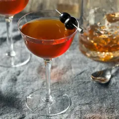 Cocktail au whisky garni de cerises, servi avec un verre de whisky et un jigger. Le whisky est-il bon pour les artères ? Une question à méditer.