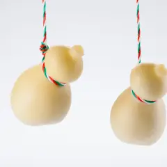 Due scamorze appese, una con la sua forma a pera, l'altra più tondeggiante. Entrambe sono legate con un filo tricolore. Ricorda che la scamorza contiene lattosio.