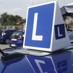 Niebieskie samochody z literą "L" na dachu, symbolizujące naukę jazdy i zasady egzaminu na prawo jazdy.