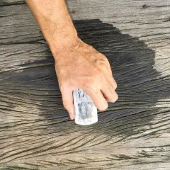 En hand håller en borste redo att skura altanen.