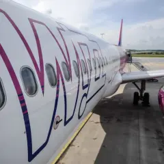 Samolot Wizz Air na płycie lotniska, widok z boku na kadłub i silnik.