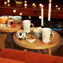Tavolini bassi con tazze a tema animale, popcorn e biscotti, perfetti per una serata cinema a casa.