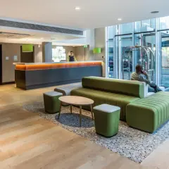 Nowoczesne lobby hotelowe, idealne miejsce, gdzie spać w Londynie z dziećmi. Wygodne sofy i recepcja czekają na gości.