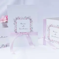 Trois faire-part de mariage délicats, ornés de fleurs pastel et de rubans roses. L'un d'eux mentionne "Rosa et Emilien".