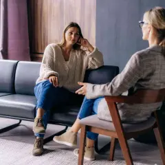 Kobieta na kozetce słucha terapeuty. Rozmowa o psychoterapii i psychologii w przytulnym gabinecie.