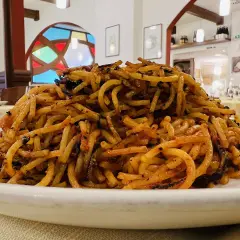 Un piatto di spaghetti con pomodoro e basilico, un classico su cosa mangiare a Bari. Il tutto servito in un ristorante con vetrate colorate.