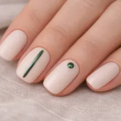 Manicure minimalista con smalto nude, una linea verde e un cristallo. L'estetista unghie ha creato un look elegante.