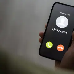 Dłoń trzyma smartfon z ekranem pokazującym przychodzące połączenie od nieznanego numeru. Czy to kolejny **wangiri**?