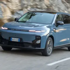 Niebieski Leapmotor B10 przemierza krętą drogę wśród skalistych zboczy.