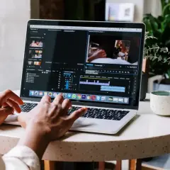 Montażysta filmów pracuje nad projektem na laptopie. Zastanawiasz się, ile zarabia montażysta filmów?